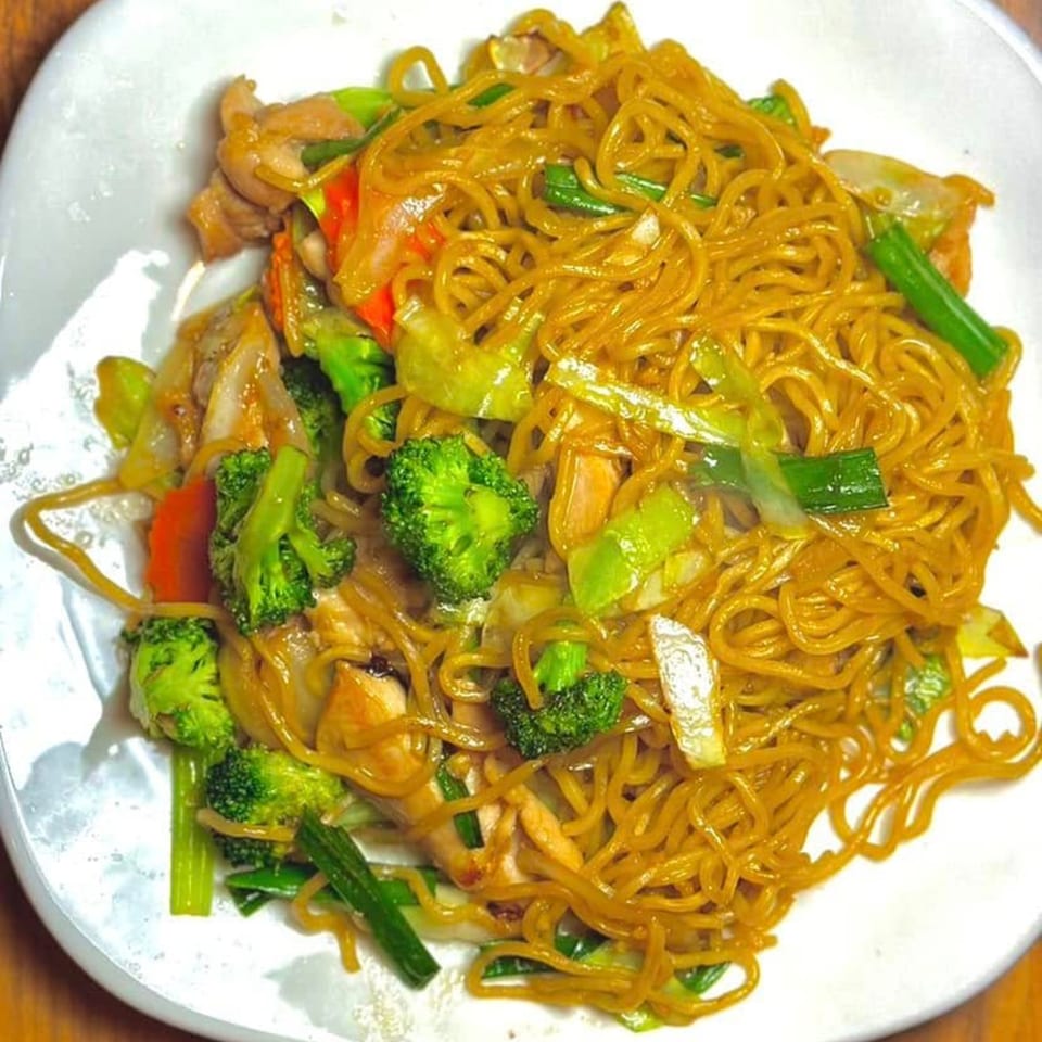 Beelicious Thai Cuisine's stir-fried noodles with chicken, broccoli, and other vegetables on a white plate.